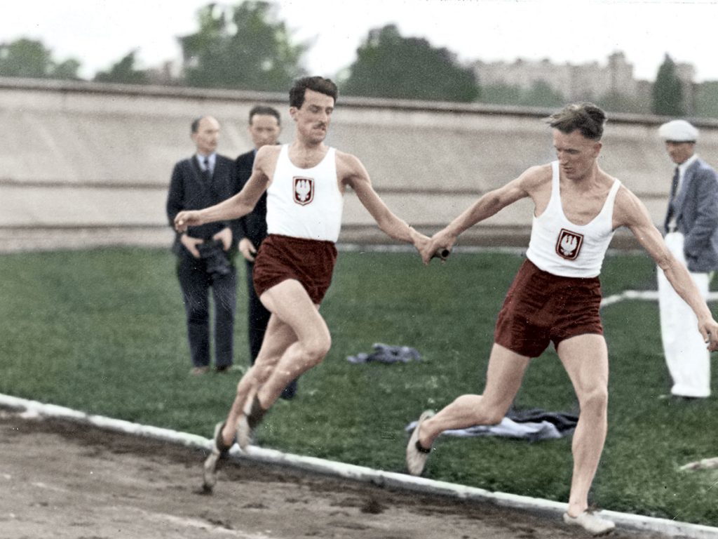 Zawody na Stadionie Wojska Polskiego im. Marszałka Józefa Piłsudskiego w Warszawie, sierpień 1934 r. Stefan Kostrzewski przejmuje pałeczkę od Kazimierza Kucharskiego w biegu sztafetowym. Źródło: Narodowe Archiwum Cyfrowe