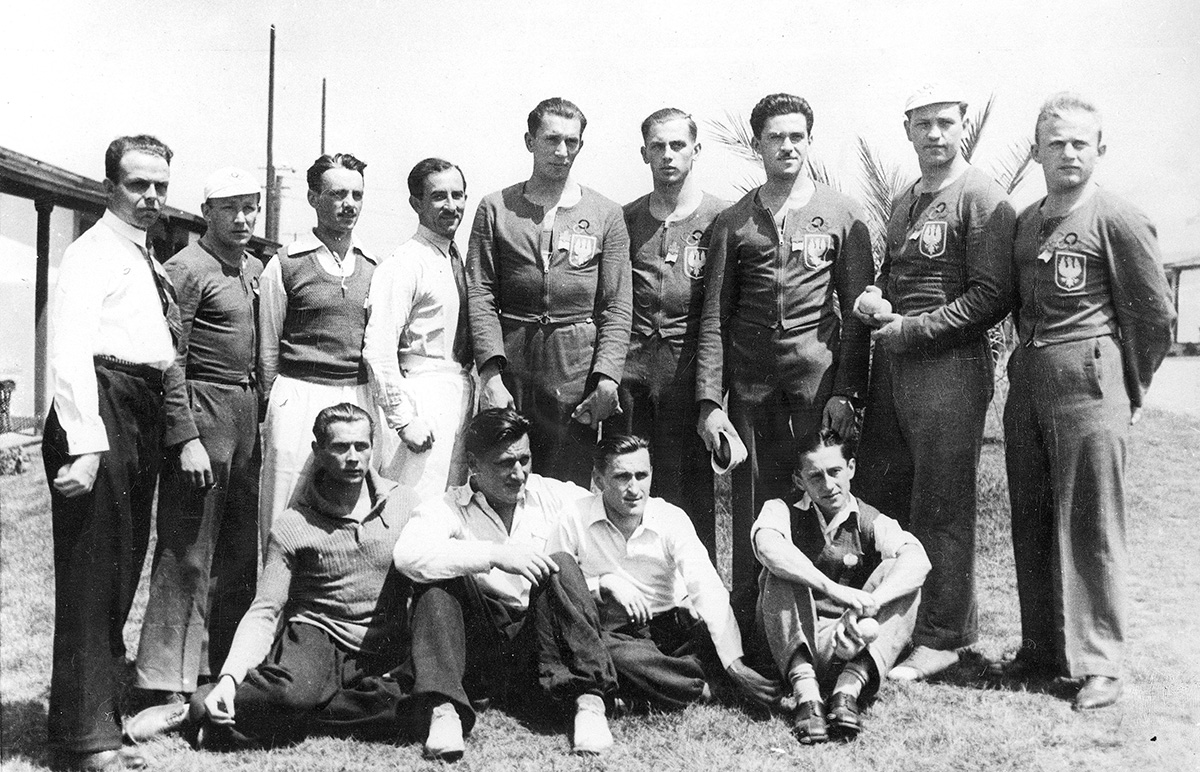 Grupa polskich sportowców w wiosce olimpijskiej w Baldwin Hills. Stoją od lewej: Tadeusz Friedrich, Jan Mikołajczak, Marian Suski, Władysław Dobrowolski, Janusz Ślązak, Jerzy Braun, Edward Kobyliński, Stanisław Urban, Henryk Budziński. Siedzą od lewej: Zygmunt Siedlecki, Zygmunt Heliasz, Janusz Kusociński i Jerzy Skolimowski. Los Angeles, 1932 r. Źródło: Narodowe Archiwum Cyfrowe