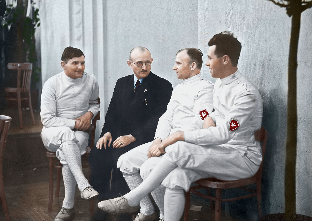 Śląscy szpadziści – Ewald Kamala (pierwszy z lewej), mistrz Polski Teodor Zaczyk (drugi z prawej) i Rajmund Karwicki (pierwszy z prawej) – w przerwie zawodów rozmawiają z fechmistrzem Leonem Kozą-Kozarskim (w garniturze). Mistrzostwa Polski w szermierce w Domu Akademickim w Warszawie, kwiecień 1938 r. Źródło: Narodowe Archiwum Cyfrowe